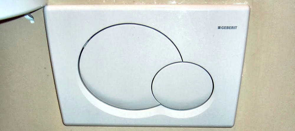 Panel on wall above toilet. On panel two slightly overlapping rounds, one big and one small.
